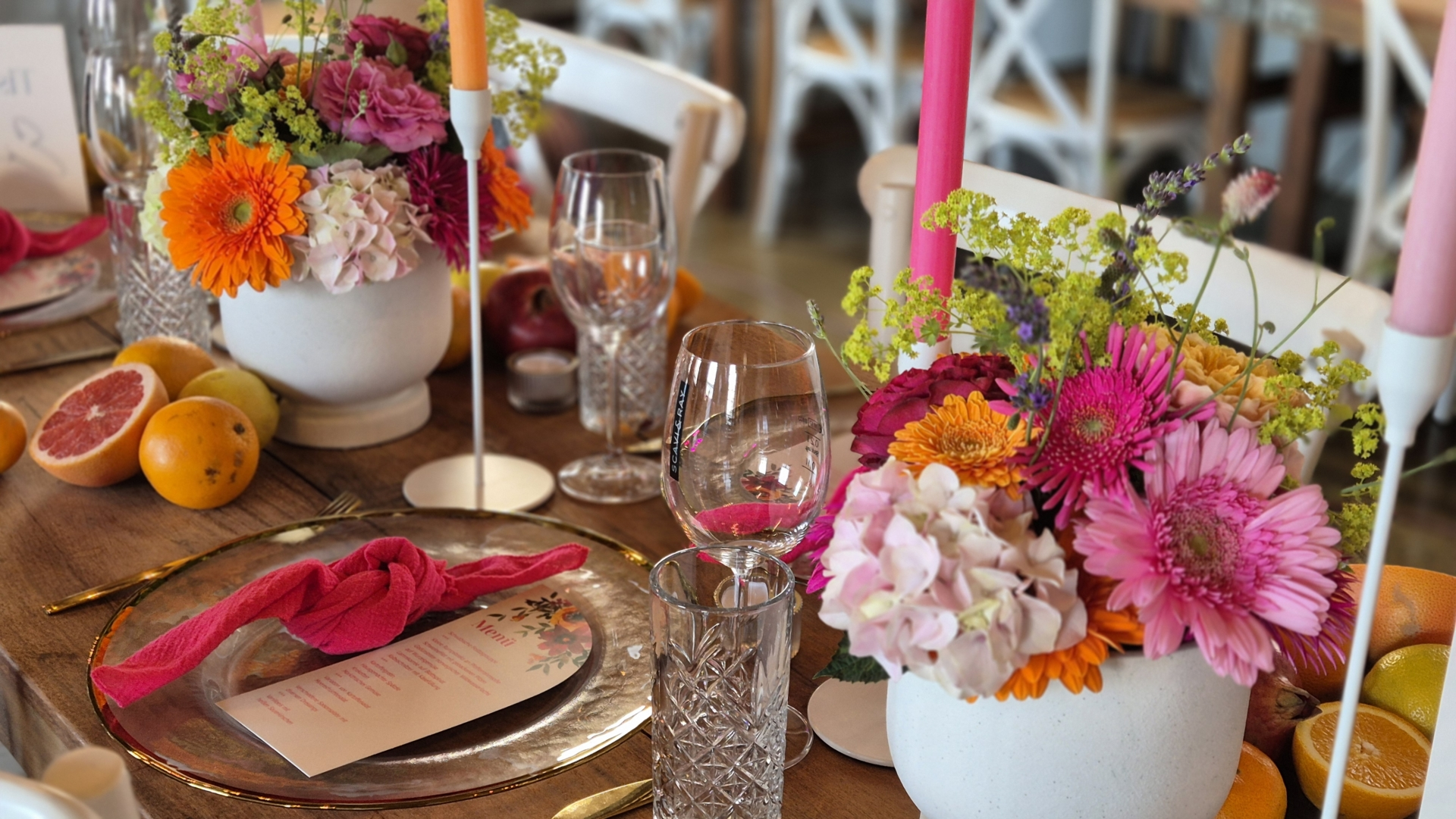 Blumenarrangement mit roten Blüten und grünen Blättern in einer runden Schale.