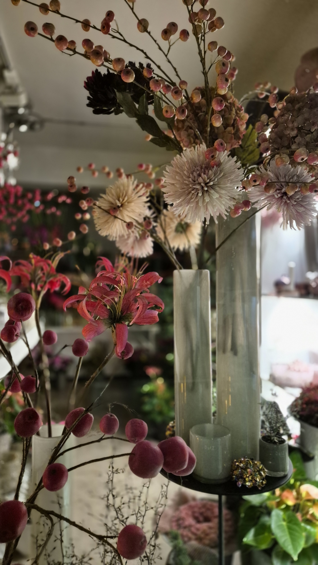 Kunstblumen in verschiedenen Farben und Formen, arrangiert in modernen Vasen auf einem Tisch.